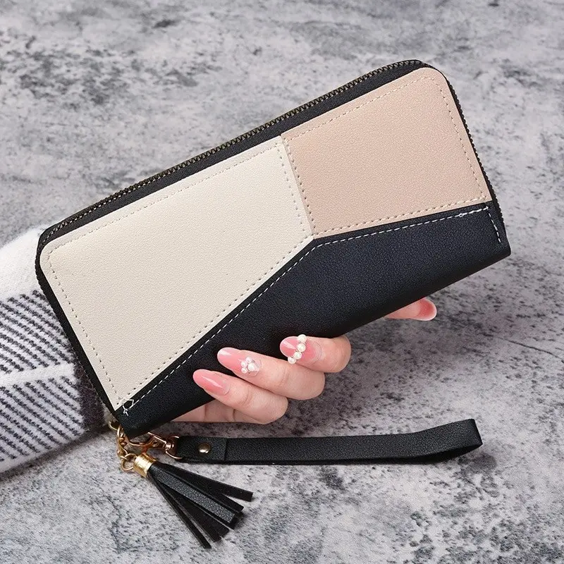 Lange Geldbörse mit Reißverschluss in Schwarz, Creme und Beige in der Hand gehalten