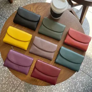 Kleine Geldbörsen in acht Farben auf einem runden Holztisch ausgebreitet