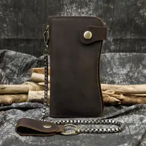 Dunkelbraune lange Lederbörse mit Druckknopf und Kette vor dunklem Hintergrund
