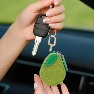 Grünes Mini-Täschchen in Birnenform mit Reißverschluss und Karabiner neben einem Autoschlüssel