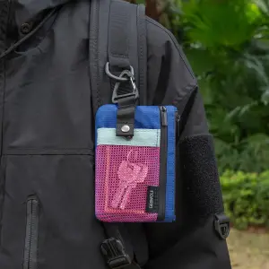 Kleine blau-pinke Umhängebörse mit Netzfach und Karabiner an einem Rucksack