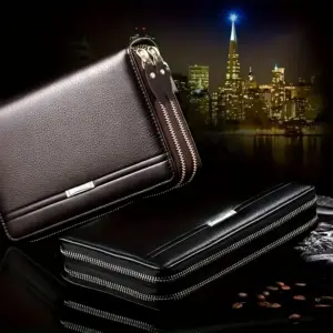 Dunkelbraune und schwarze Reißverschluss-Clutch-Geldbörsen mit Metallspange auf dunklem Untergrund